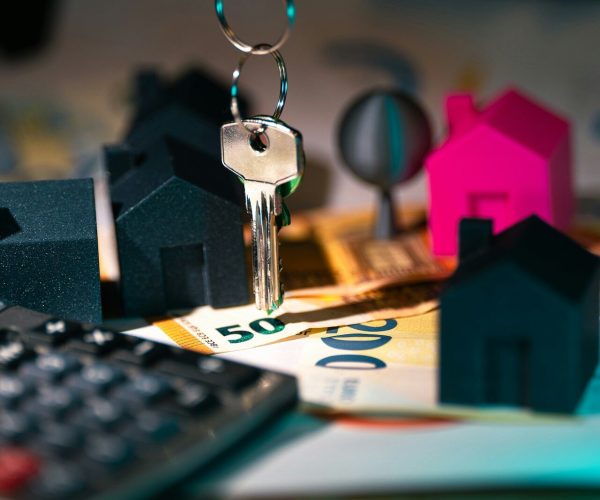 A calculator, keychain, and house model on a table